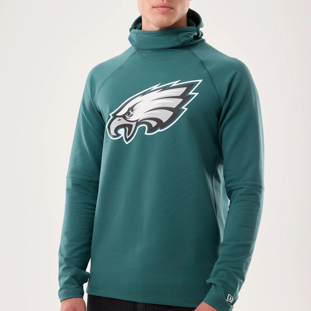New Era Philadelphia Eagles NFL Sideline 2026 Dark Green Balaclava Hoodie, front view on a model showing the large printed team eagle logo across the chest, a high neck with balaclava style collar.