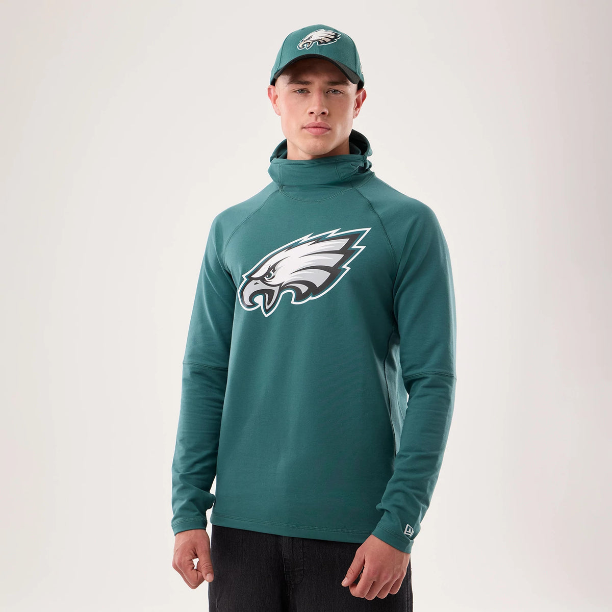 New Era Philadelphia Eagles NFL Sideline 2026 Dark Green Balaclava Hoodie, front view on-model displaying a large printed Eagles logo centred on the chest, long sleeves with an embroidered New Era logo on the cuff, and a high neck design.