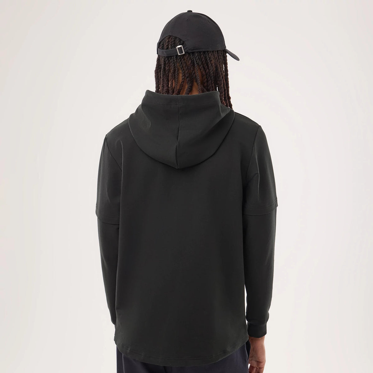 New Era Denver Broncos NFL Sideline 2026 Black Double Sleeve Hoodie, back view on a model showing the relaxed black hoodie with a generous hood, double sleeve detail at the shoulders and plain lower back, paired with a black cap.
