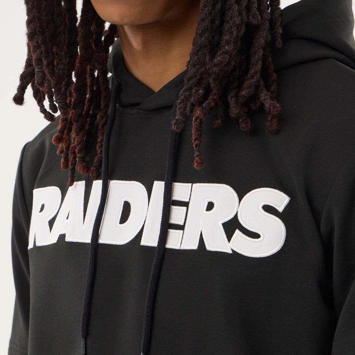 New Era Las Vegas Raiders NFL Sideline 2026 Black Double Sleeve Hoodie, front view showing white embroidered RAIDERS lettering across the chest, with a drawstring hood detail at the neckline on a model.
