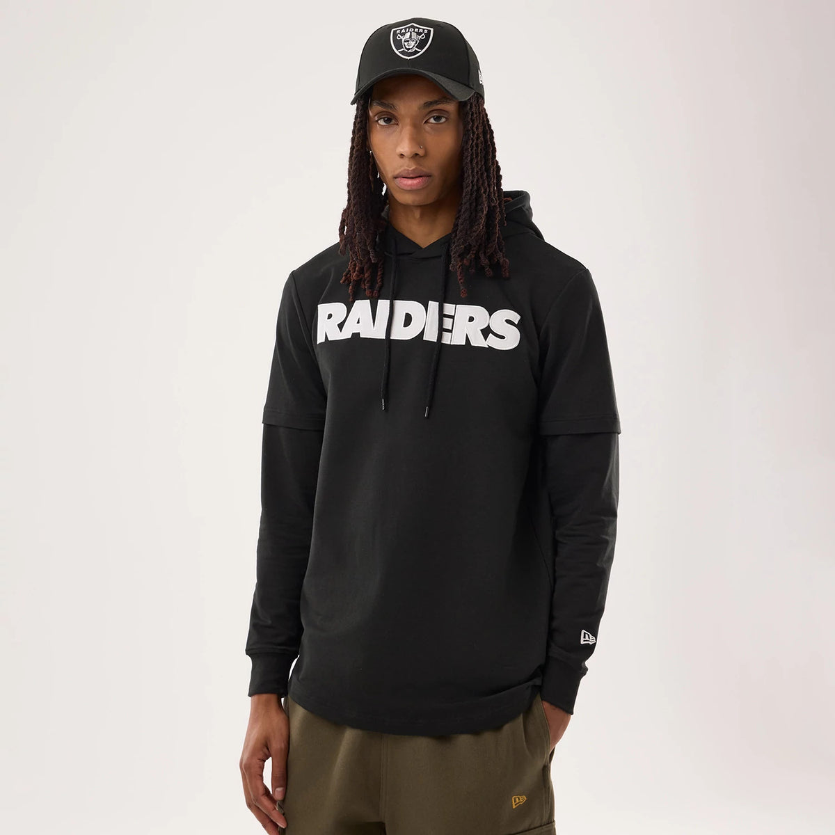 New Era Las Vegas Raiders NFL Sideline 2026 Black Double Sleeve Hoodie, front view on-model displaying white embroidered RAIDERS across the chest, layered long sleeves, and a white embroidered New Era logo on the lower left sleeve.