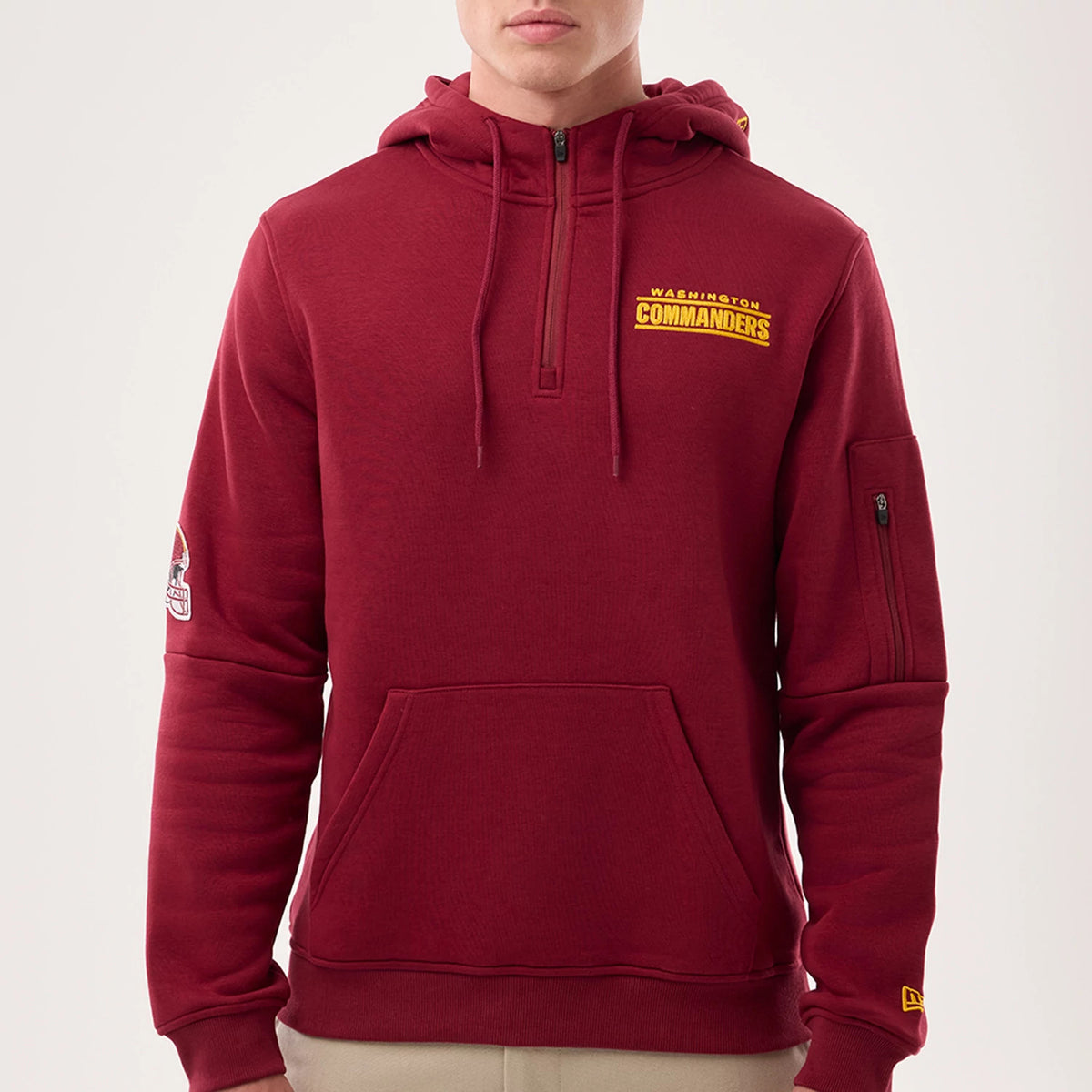New Era Washington Commanders NFL Sideline 2026 Dark Red Pullover Hoodie, front view showing the embroidered Washington Commanders logo on the chest, a zipped pocket on the sleeve, and a New Era logo on the cuff, styled casually on a model.