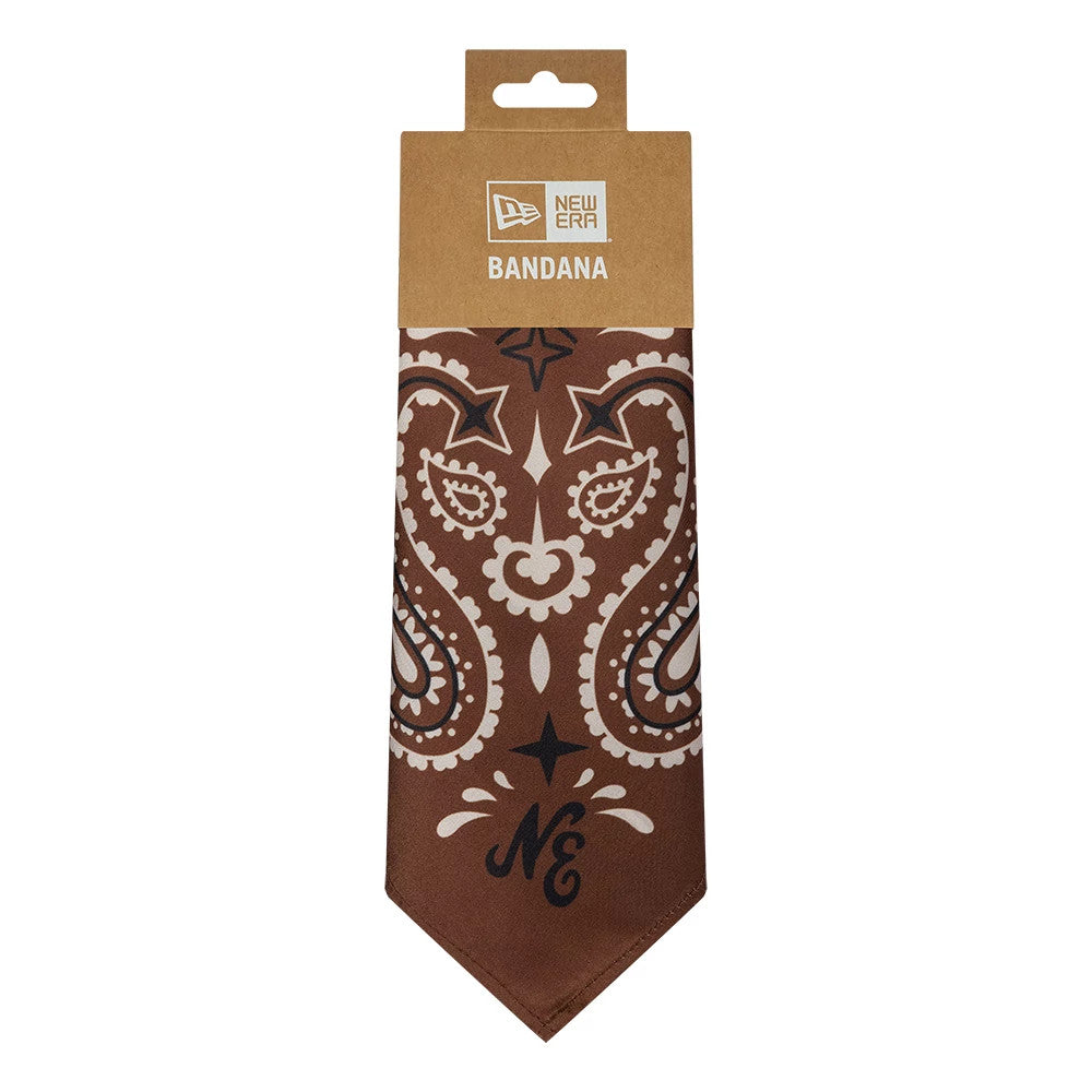 New Era Paisley Satin Brown Bandana, front view showing intricate white and black paisley designs on a rich brown satin fabric with the NE initials prominently displayed, packaged with a kraft paper hanger featuring the New Era logo.