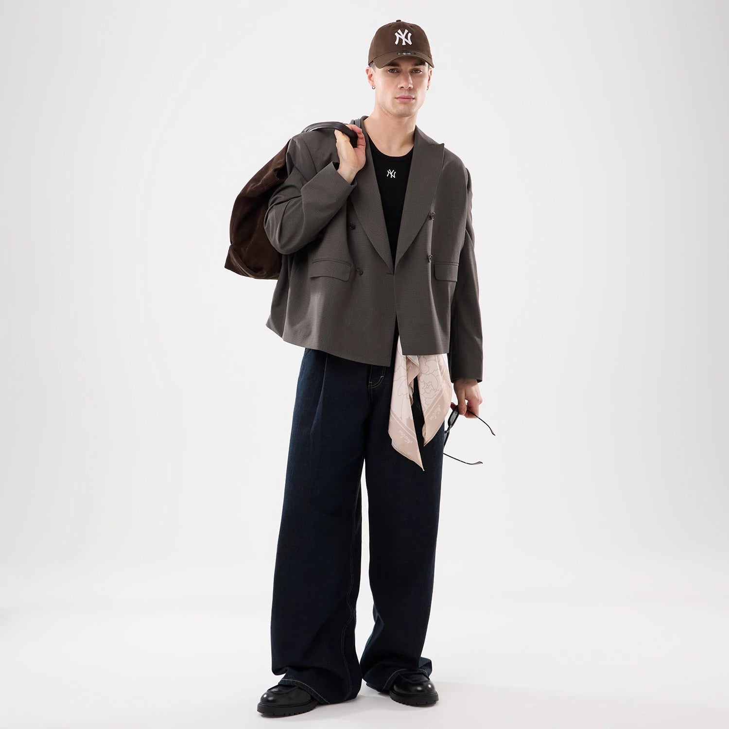 New Era Floral Satin Beige Bandana, on a model styled with a beige cap and beige bandana over a layered outfit, including a grey jacket and wide-legged denim trousers, with the bandana draped from the model's waist.
