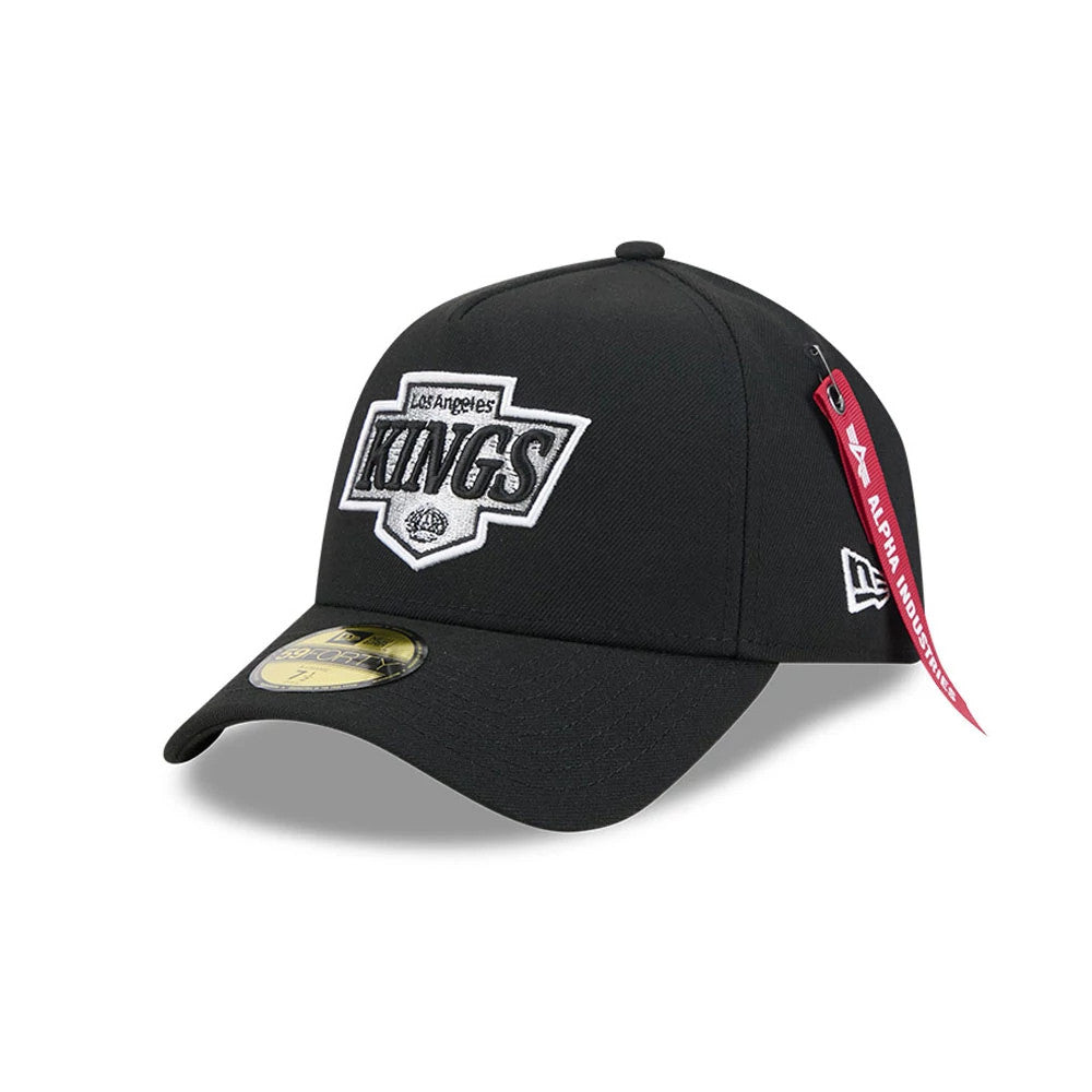 LA Kings NHL X Alpha Black New Era 59FORTY A-Frame Fitted Cap, three-quarter view showing the raised embroidered Kings logo in black and white on the front panel, with a gold 59FORTY size sticker on the black visor and red Alpha Industries tag.