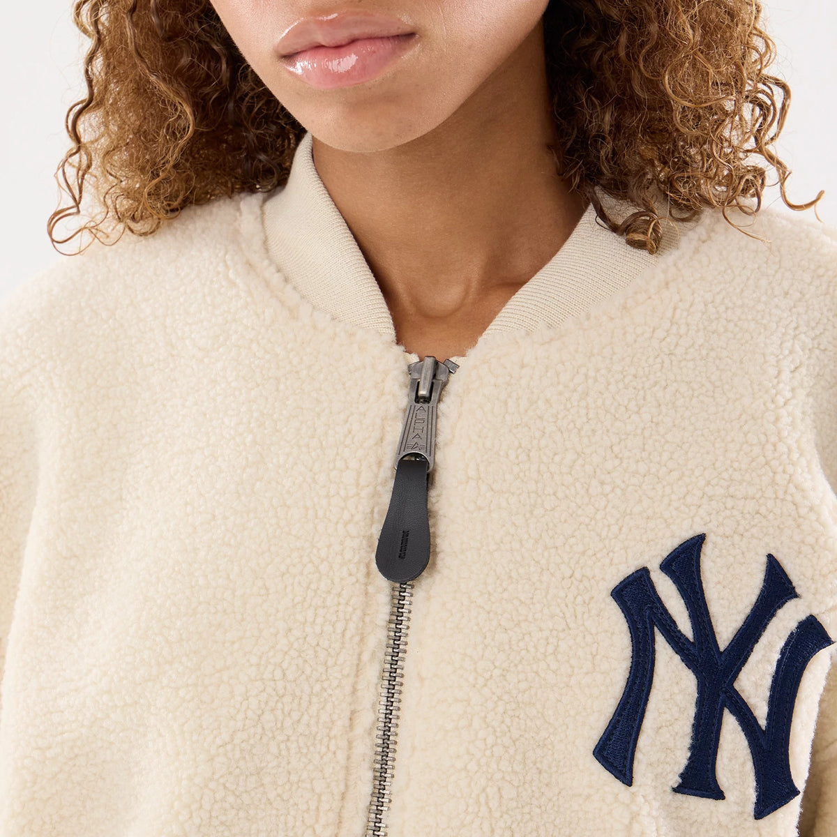 New Era New York Yankees MLB X Alpha Cream Borg Jacket, front view on-model highlighting the cream-coloured borg material with a central zip closure, ribbed collar, and a prominent navy blue embroidered New York Yankees logo on the left side.