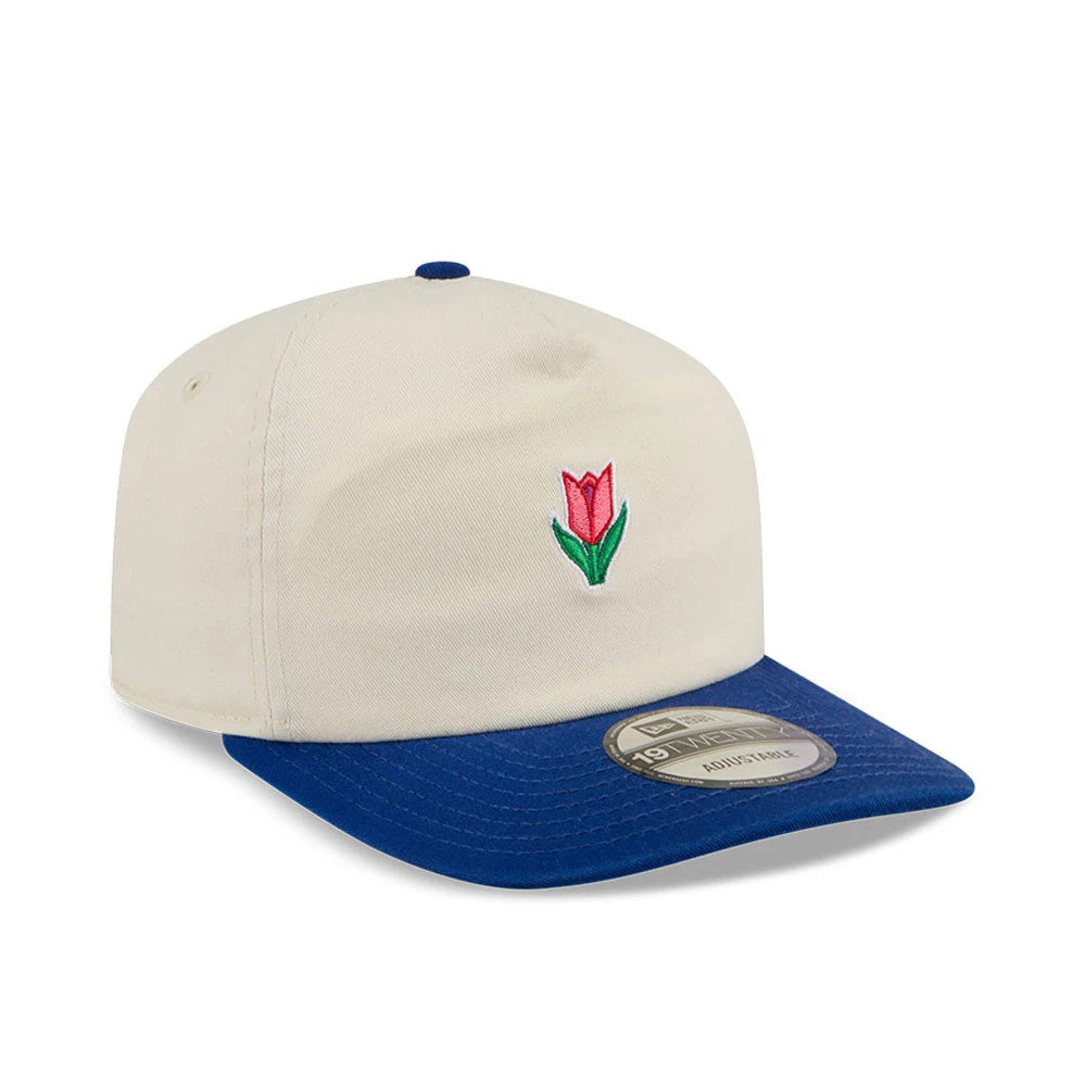 New Era Tulip Cream 19TWENTY Adjustable Cap, three-quarter view showing a pink and green tulip embroidered on the cream front panels, a blue curved visor with a 19TWENTY size sticker and a matching blue top button.