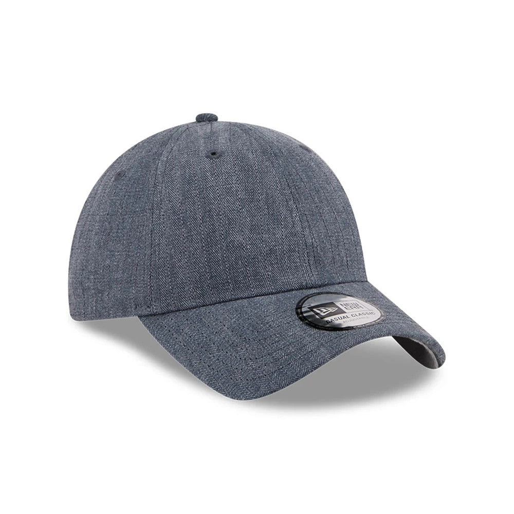 New Era Herringbone Pinstripe Navy Casual Classic Adjustable Cap, three-quarter view showing the detailed herringbone pattern on the textured navy fabric, along with the curved visor and the black and white Classic size sticker on the visor.