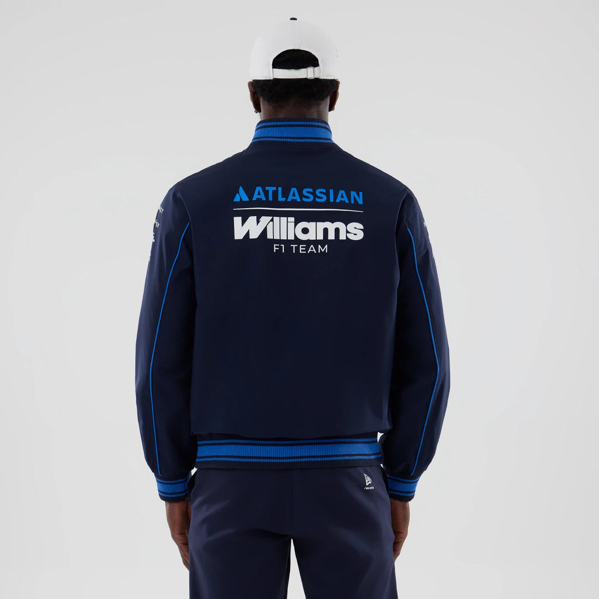 New Era Williams Navy Varsity Jacket, back view on a model showing large printed Williams F1 Team logo centred on the upper back, Atlassian branding above, and featuring blue stripe along the sleeves and ribbed collar and waistband.