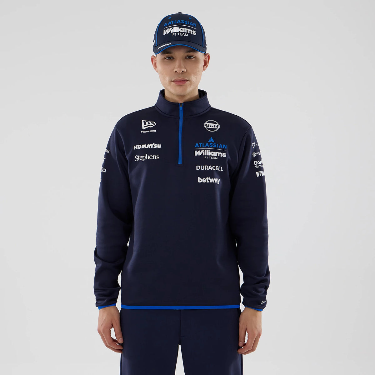 New Era Williams Navy Mid Layer 1/4 Zip Sweater, front view on a model wearing a matching navy cap, featuring multiple sponsor logos across the chest, a quarter zip running down from the collar, and blue piping along the hem.