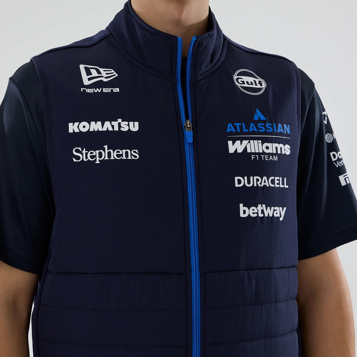 New Era Williams Navy Gilet, front view on a model featuring prominent sponsor logos including Gulf, Atlassian and Williams F1 Team in white and blue across the chest, with a blue zip on the dark navy fabric.