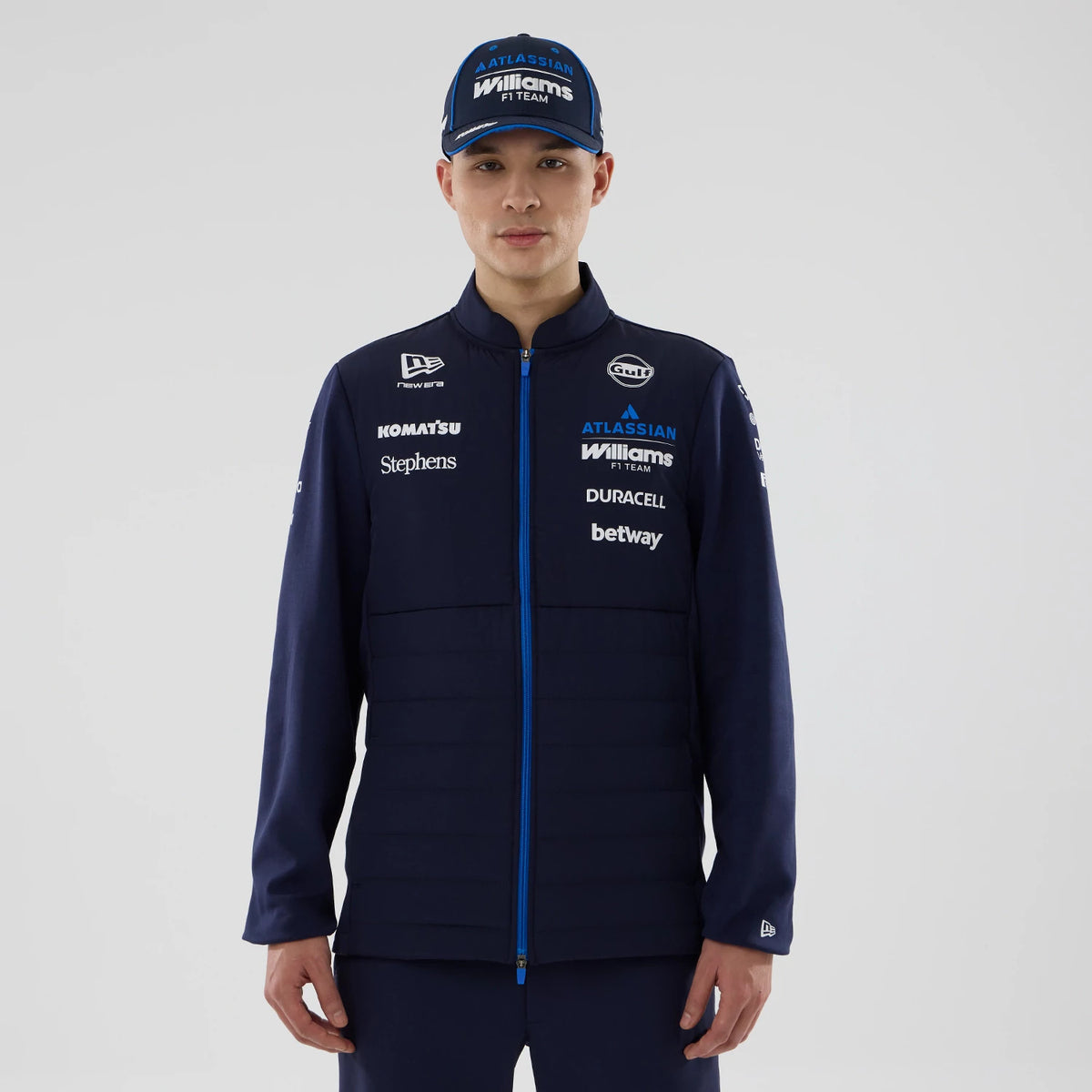 New Era Williams Navy Hybrid Jacket, front view showing prominent white printed sponsor logos along the chest and sleeves, a blue zip closure down the centre, and a small embroidered New Era logo on the left cuff.