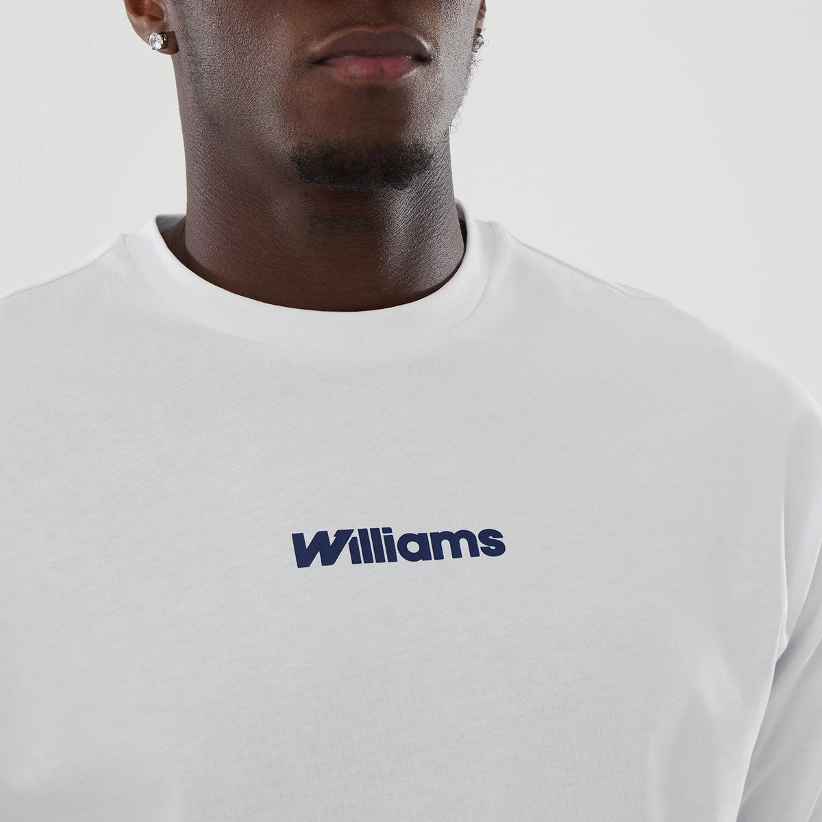 New Era Williams Japan 1996 Script White Oversized T-Shirt, front view on-model showing the navy blue printed Williams logo centred on the chest, featuring a round neckline and short sleeves, styled in a simple and modern fashion.