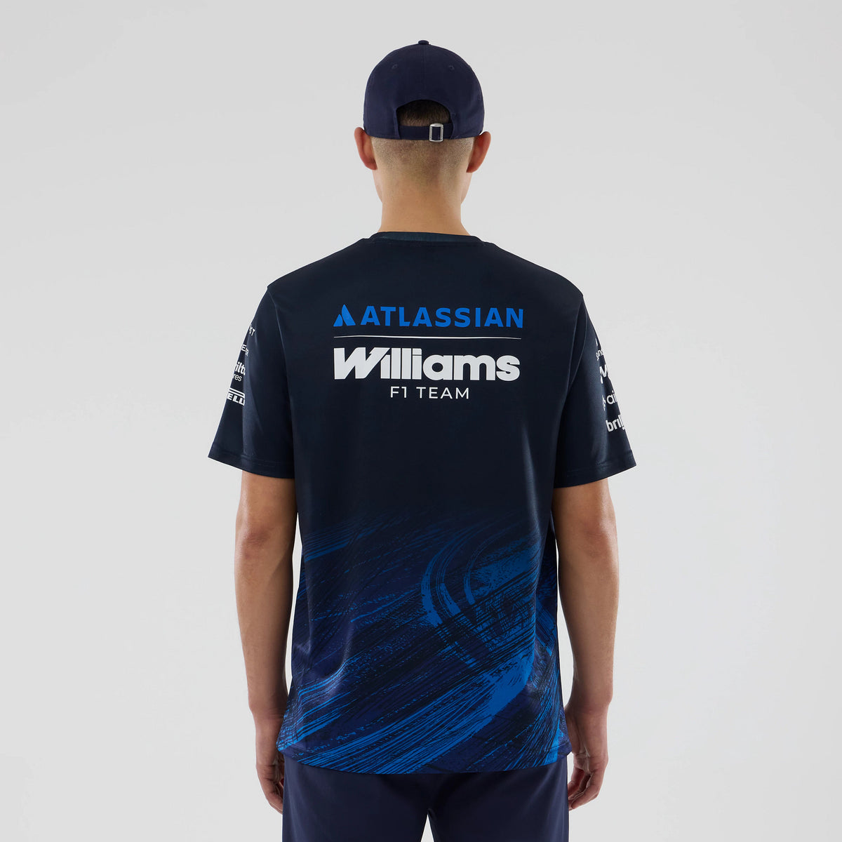 New Era Williams Navy Tech T-shirt, back view on-model showing the Atlassian and Williams F1 Team lettering across the back in contrasting white and blue, with dynamic blue graphic details on the lower part of the navy fabric.