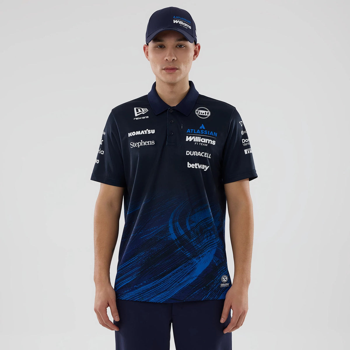 New Era Williams Navy Tech Polo T-shirt, front view on a model showing multiple sponsor logos across the chest and sleeves, an abstract blue design at the bottom, a three-button placket, and a small embroidered New Era logo on the right chest.