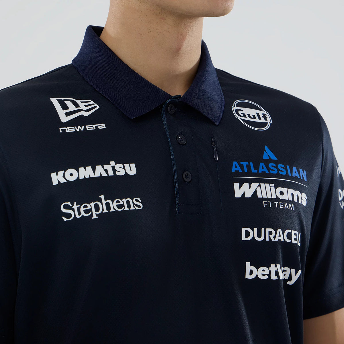 New Era Williams Navy Tech Polo T-shirt, front view on-model showing the dark navy collar with a row of buttons, a white printed New Era logo on the right chest, and various sponsor logos including Gulf and Williams F1 Team prominently displayed.