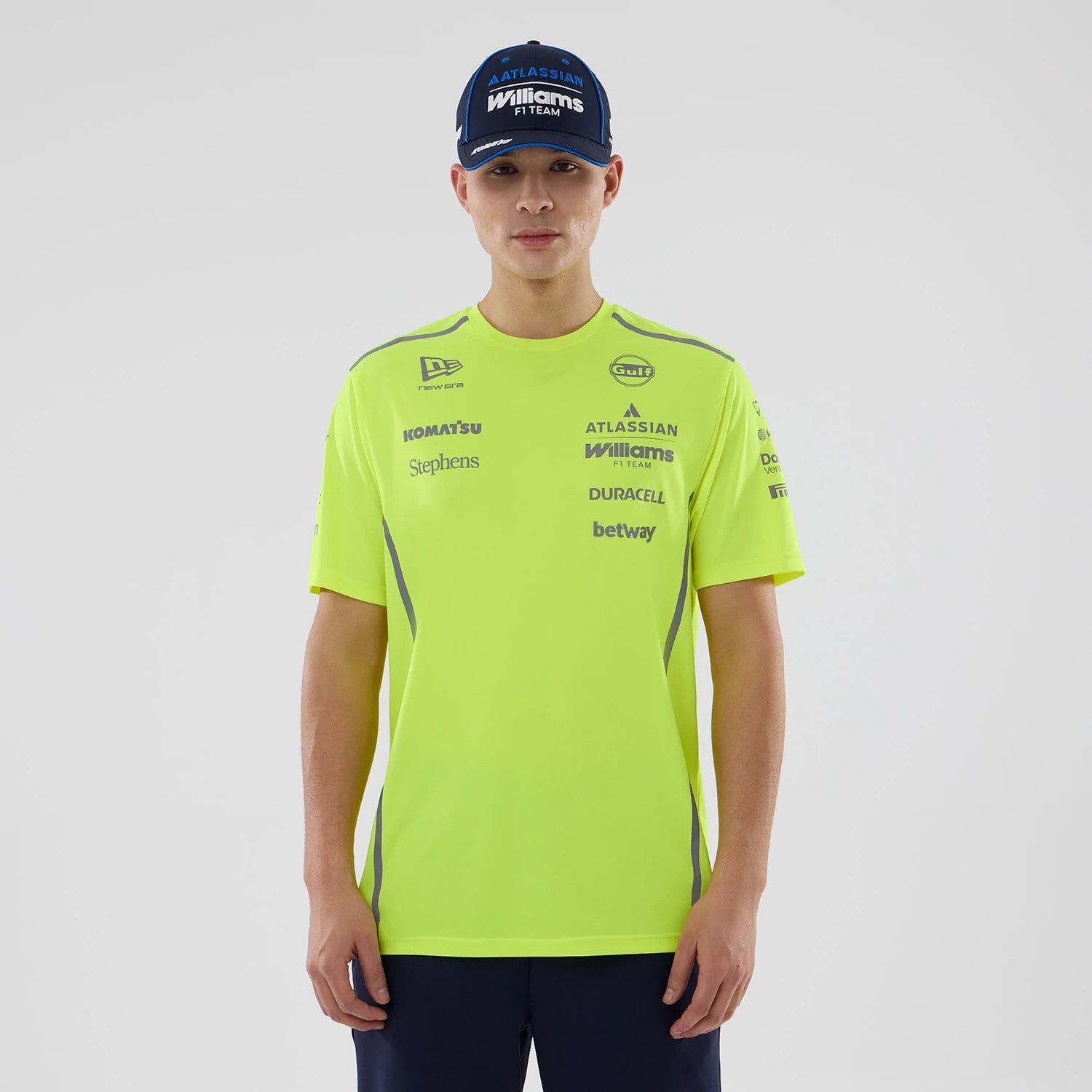 New Era Williams Set Up Yellow T-Shirt, front view on a model, featuring multiple sponsor logos including Williams F1 Team, Duracell, and betway printed in blue and black on the yellow fabric, with a New Era logo near the shoulder.