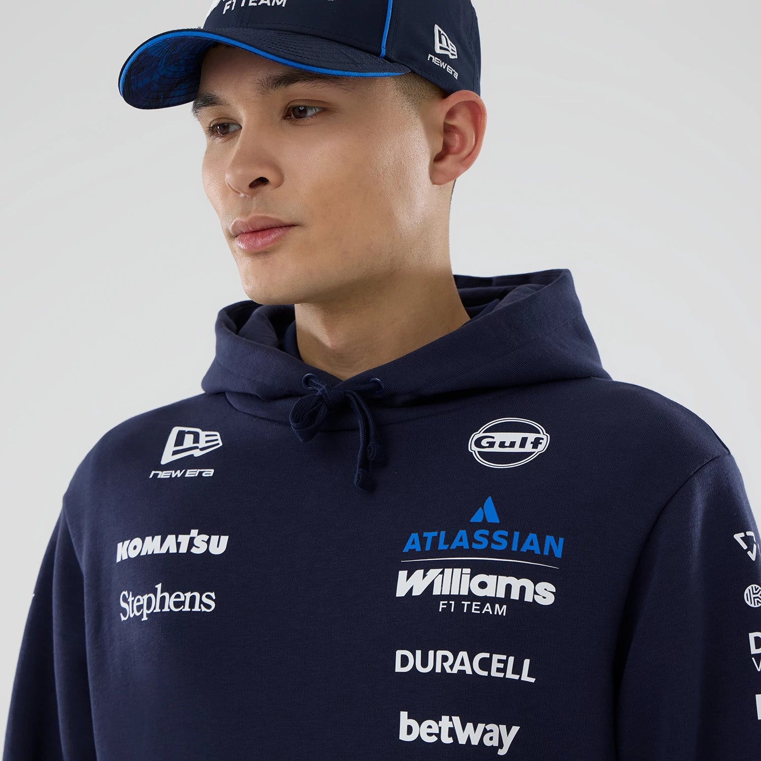 New Era Williams Replica Navy Pullover Hoodie, on-model front view showing multiple embossed logos including New Era on the right chest, Gulf and Williams F1 Team on the left chest, and other sponsors scattered across the front.