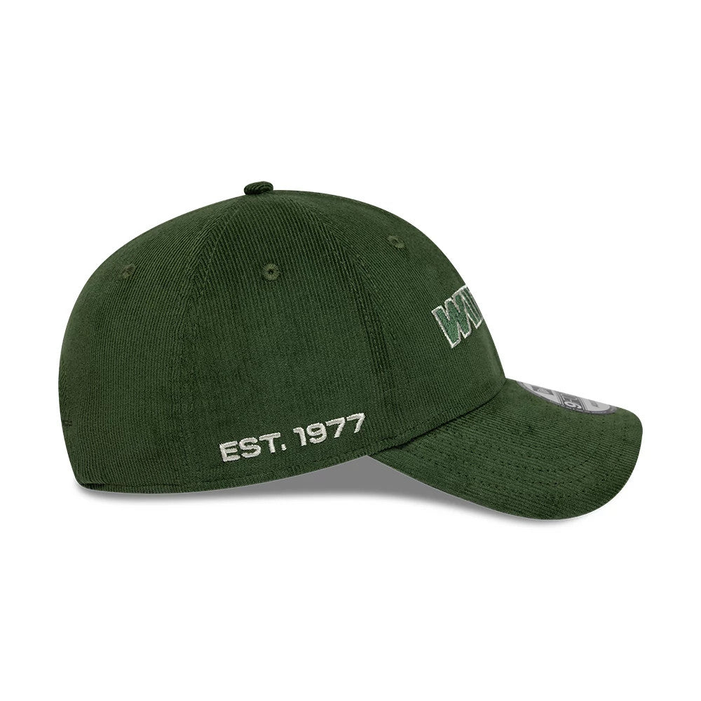 Williams Traditional Cord Dark Green New Era 9FORTY Adjustable Cap, side view showing the white embroidered EST. 1977 text on the side panel, a structured dark green corduroy crown, and a dark green curved visor with a 9FORTY size sticker.