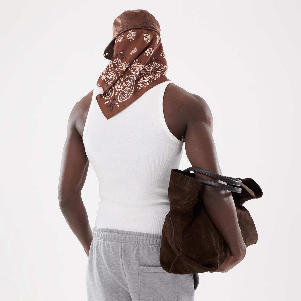 New Era LA Dodgers MLB Rib White Vest, rear view on a model wearing a brown headscarf and holding a brown suede bag, showing the vest's ribbed texture and sleeveless design, paired with grey casual trousers.