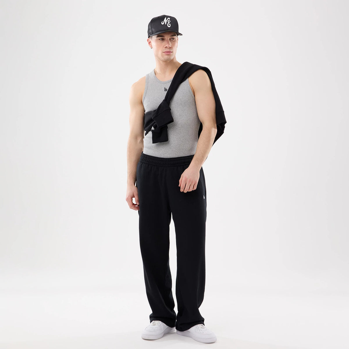 New Era LA Dodgers MLB Rib Grey Vest, front view on a model wearing the vest paired with black trousers and a black cap, showing the embroidered LA Dodgers logo on the chest, complemented by a casually draped black jacket.