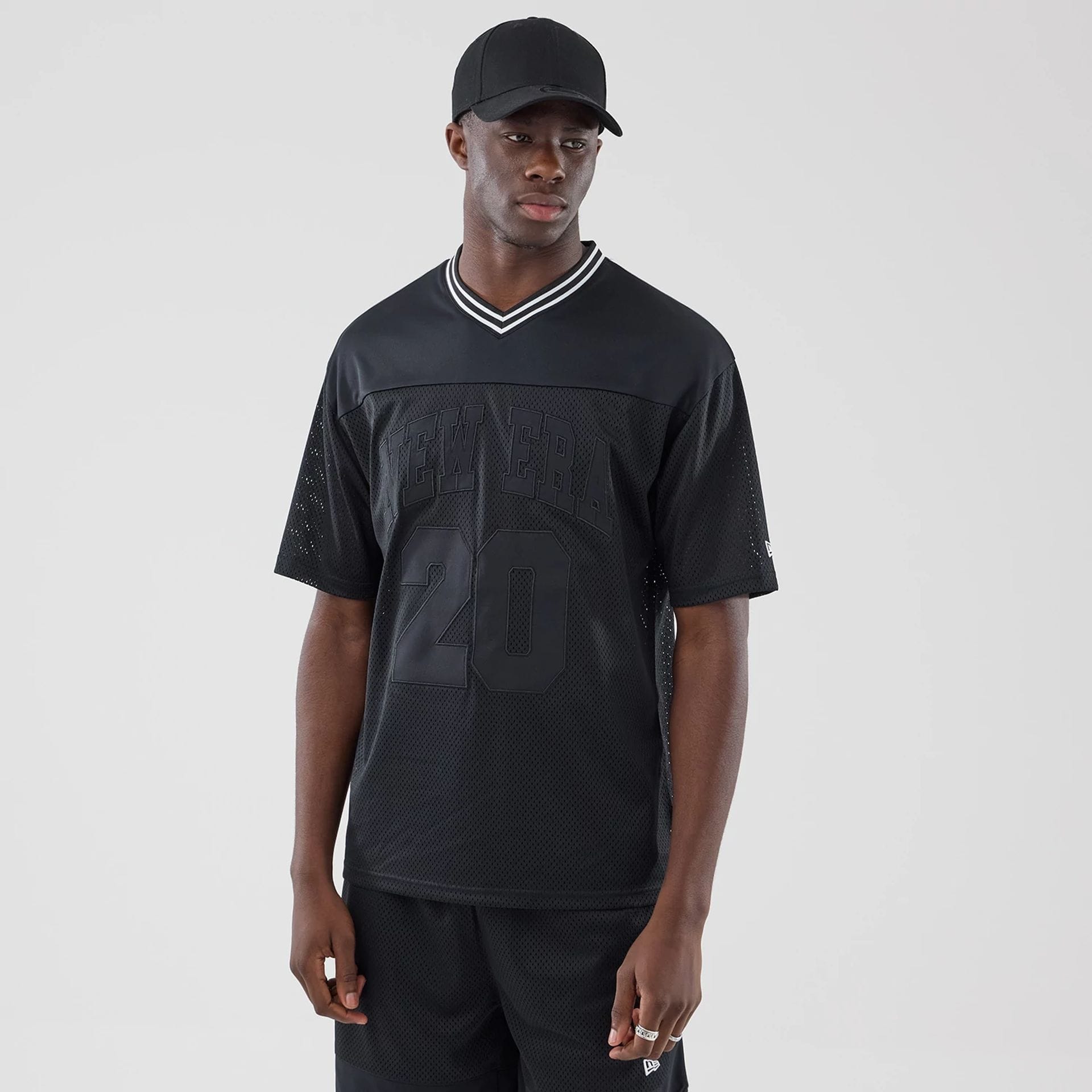 The model is wearing this New Era Mesh Oversized T-Shirt in black. 1