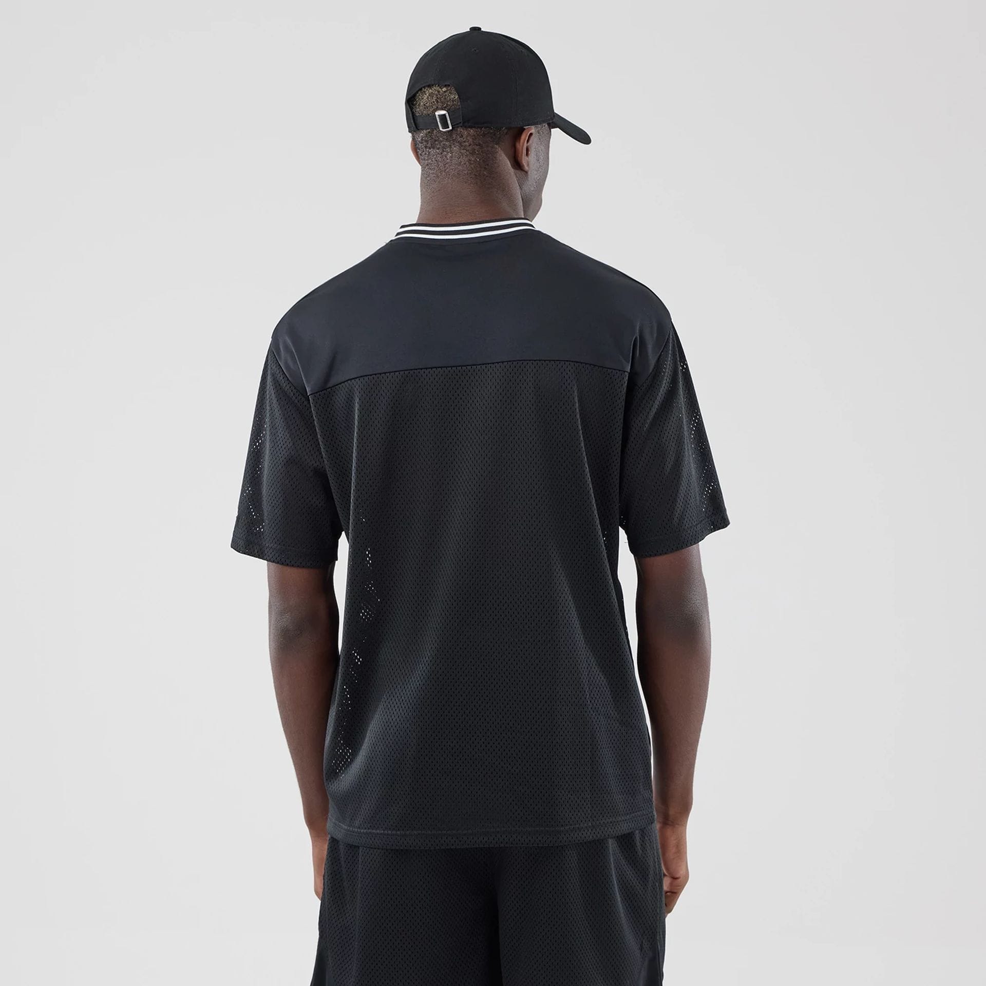 The model is wearing this New Era Mesh Oversized T-Shirt in black. 2