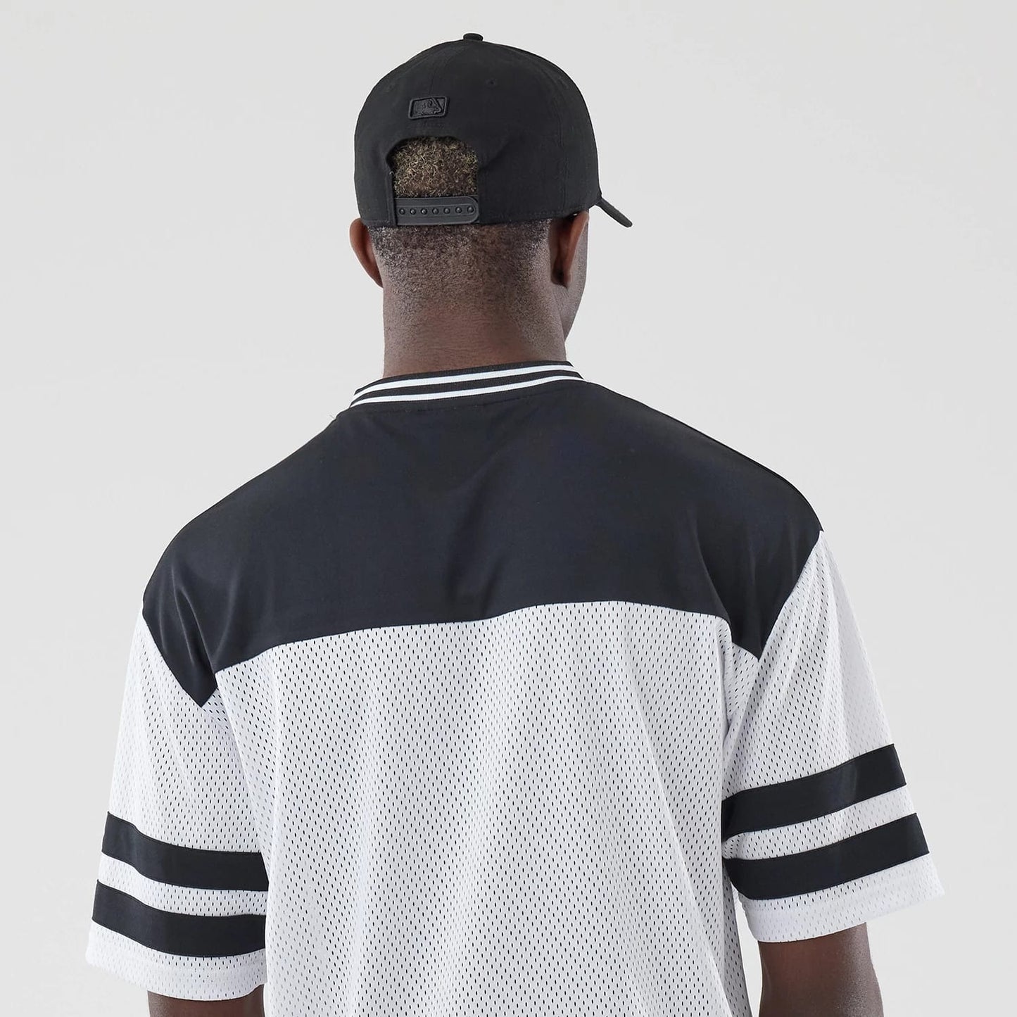 The model is wearing this New Era Mesh Oversized T-Shirt in white. 7