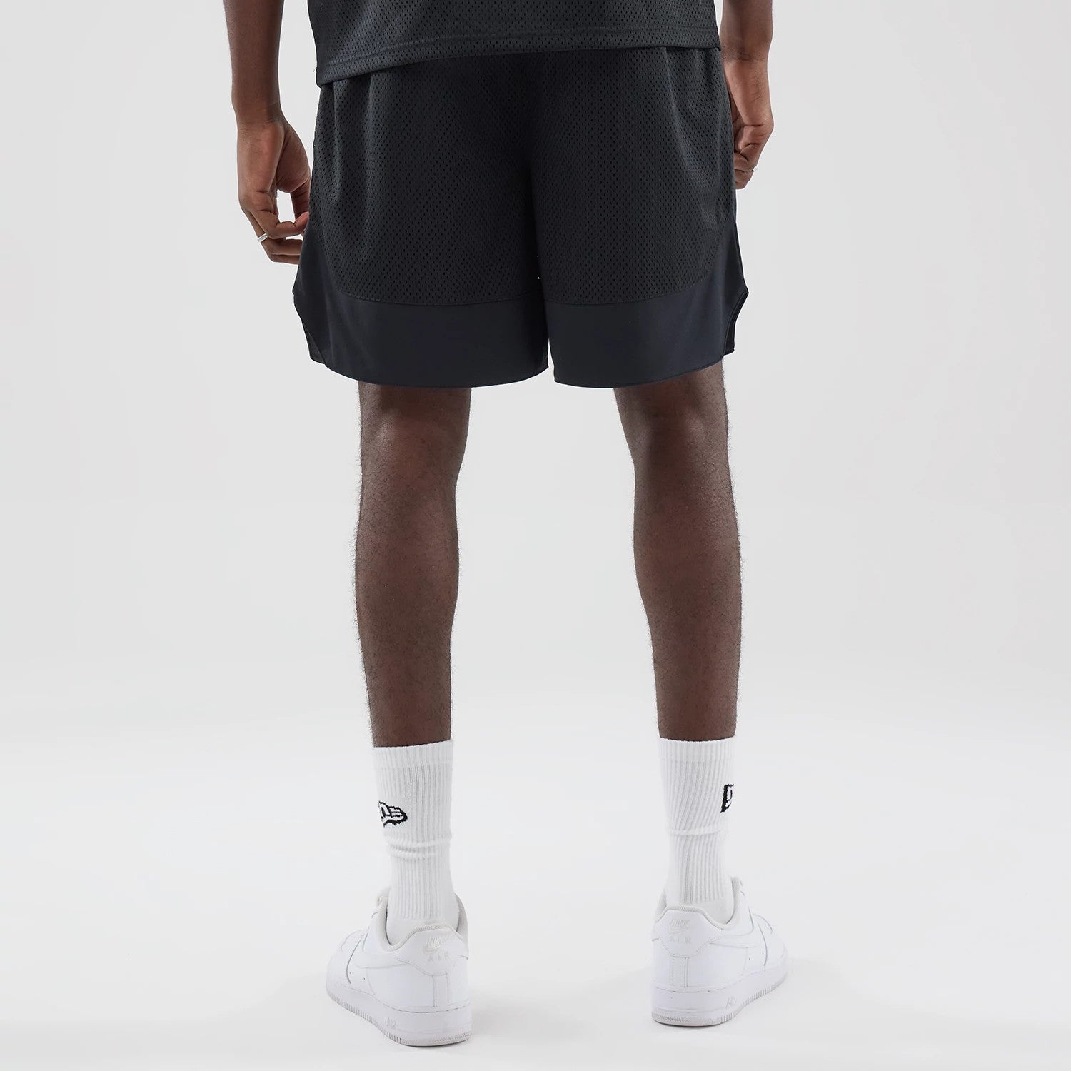 The model is wearing this New Era Mesh Stripe Oversized Shorts in black. 2