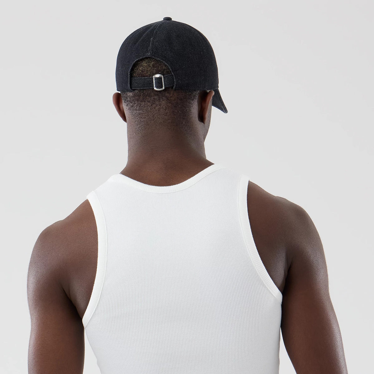 New Era Rib White Vest, rear view on a model wearing a black cap, highlighting the ribbed texture of the white vest, sleeveless design, and the fitted cut over the shoulders and upper back.
