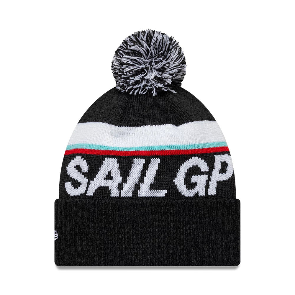 New Era Sail GP Sport Black Cuff Knit Beanie, front view showing the prominent black and white pom-pom at the top, a SAIL GP knitted design across the front, and a striped white, turquoise, and red band above the cuff.