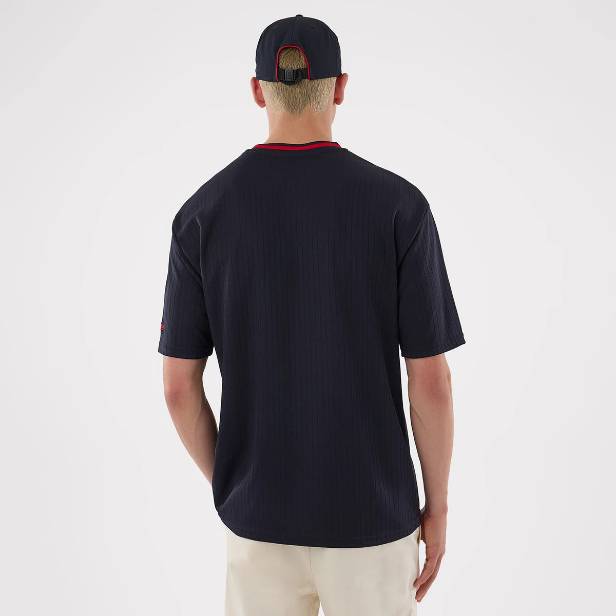 New Era New York Yankees MLB Navy Oversized T-Shirt, back view on a model wearing a matching navy cap, showing plain navy fabric with pinstripes, contrasting red neckline on the T-shirt and a red embroidered New Era logo on the sleeve.