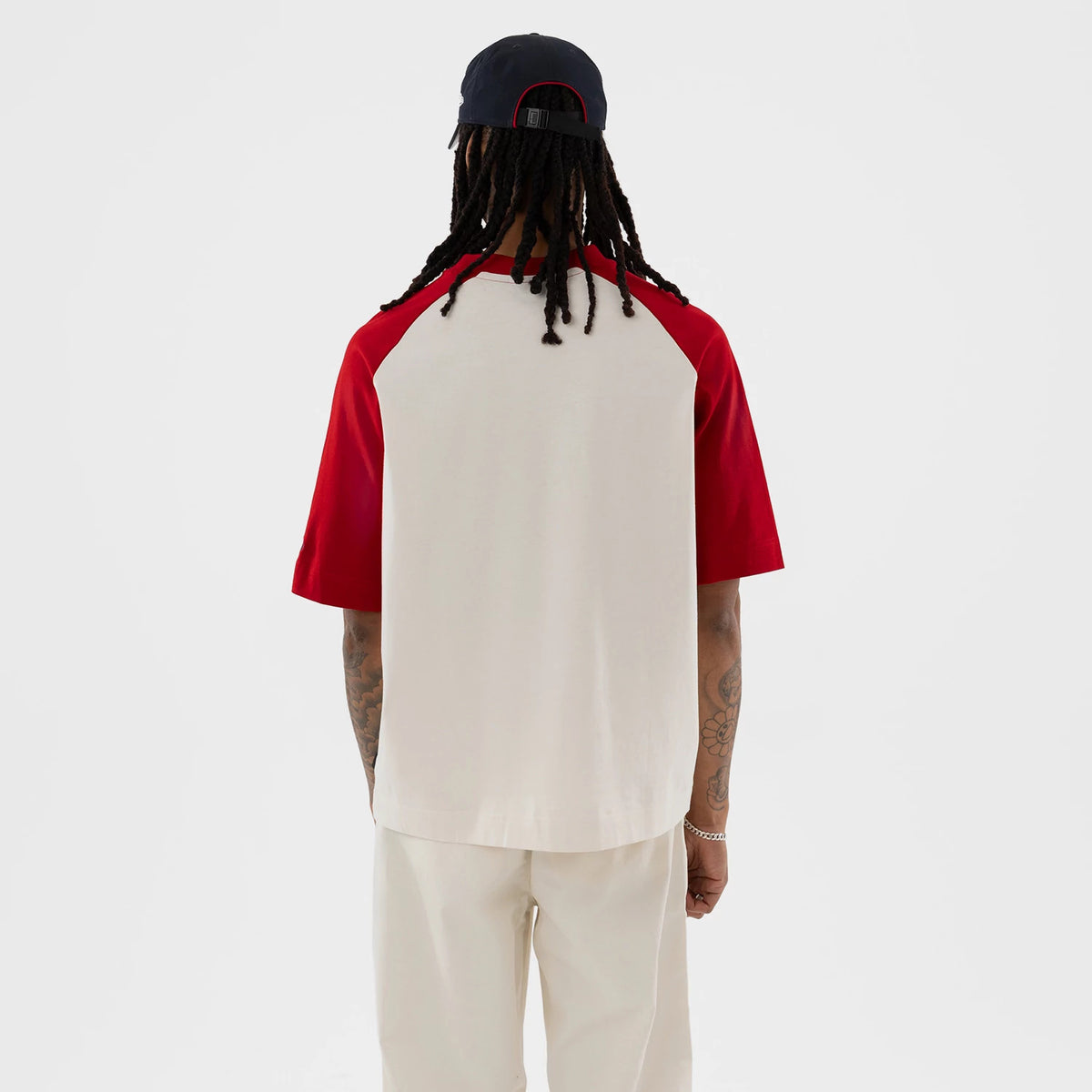 New Era New York Yankees MLB Open White Boxy T-Shirt, back view on a model showing contrasting red sleeves and a plain white back panel, styled casually with cream trousers and a dark cap.