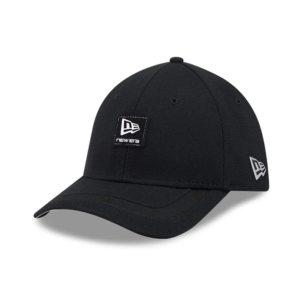 New Era Golf Rubber Patch Black 39THIRTY M-Crown Stretch Fit Cap, three-quarter view showing a black patch with a white New Era logo on the front panel, a curved black visor, and a grey embroidered New Era flag logo on the left side.