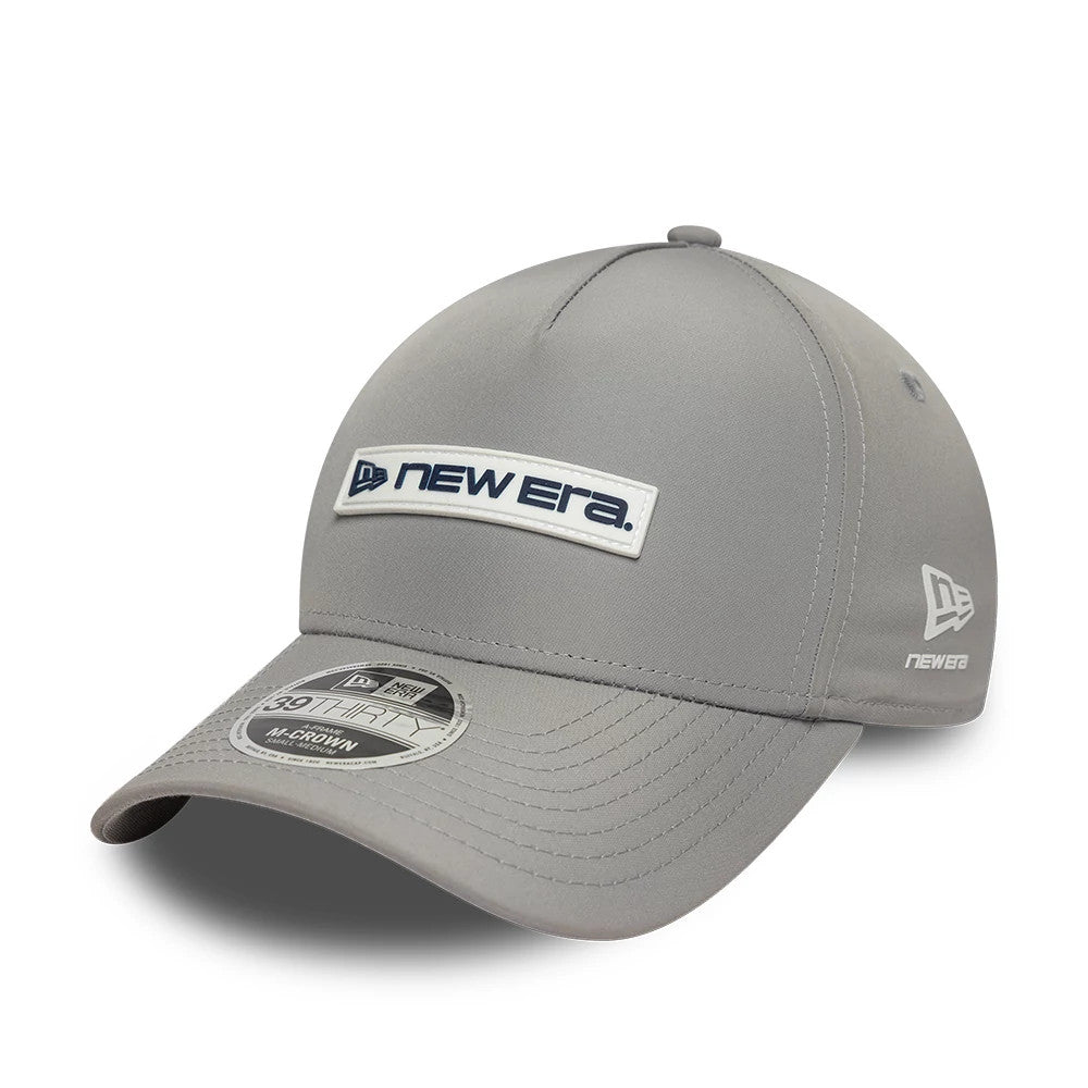 New Era Rubber Patch Grey 39THIRTY M-Crown A-Frame Stretch Fit Cap, three-quarter view showing a white and navy New Era logo patch on the front panel, a curved grey visor with a 39THIRTY size sticker.