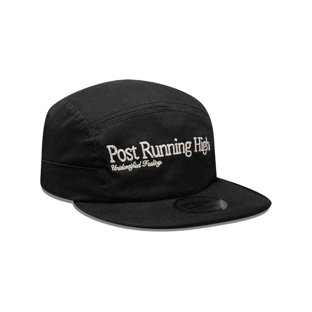 New Era X Hermanos Koumori Running Black Camper Cap, three-quarter view showing white Post Running High and Undisturbed Feelings embroidery on the front panel, a flat black visor with a New Era logo, and a structured crown.