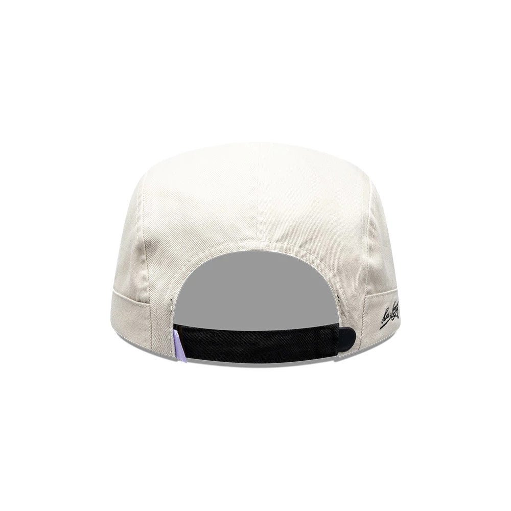 New Era X Hermanos Koumori Running Light Beige Camper Cap, rear view showing a black adjustable strap with a buckle at the back, a small purple tab detail, and delicate embroidered logo on the right side of the light beige crown.