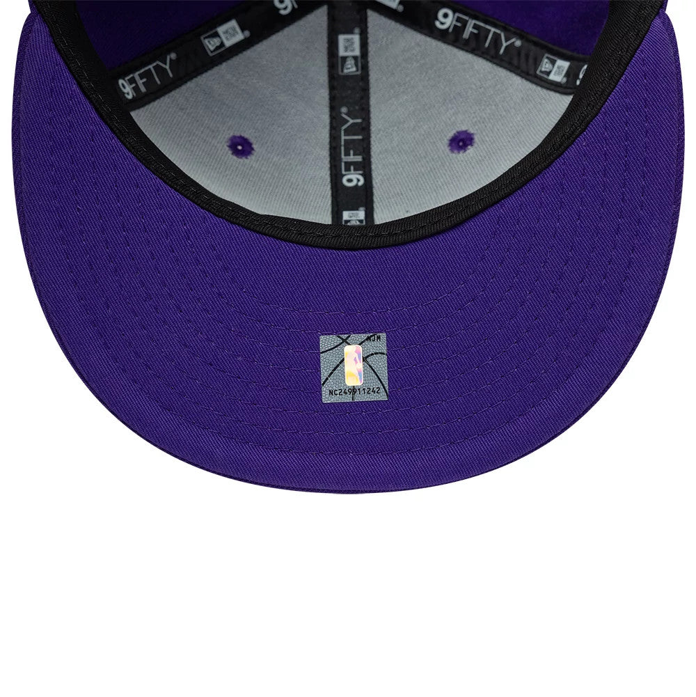 LA Lakers NBA Purple New Era 9FIFTY Snapback Adjustable Cap, inside view showing the black 9FIFTY taping along the seams, purple undervisor with a small NBA holographic sticker, and a grey sweatband providing a contrast.