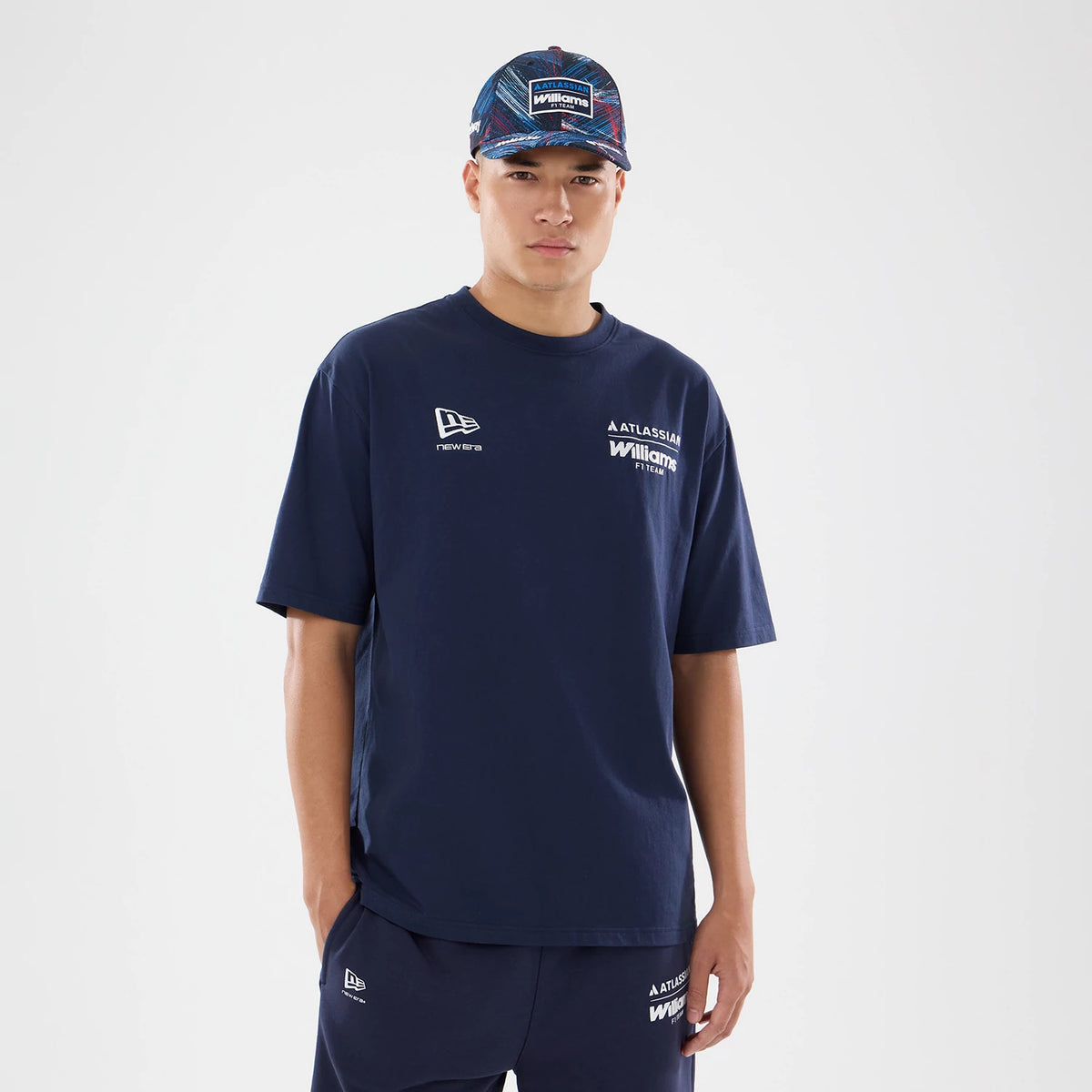 New Era Williams GB Race Special Navy T-Shirt, front view on a model wearing matching shorts and cap, displaying printed Williams and Atlassian logos on the left chest, a printed New Era logo on the right chest, and a relaxed fit design.