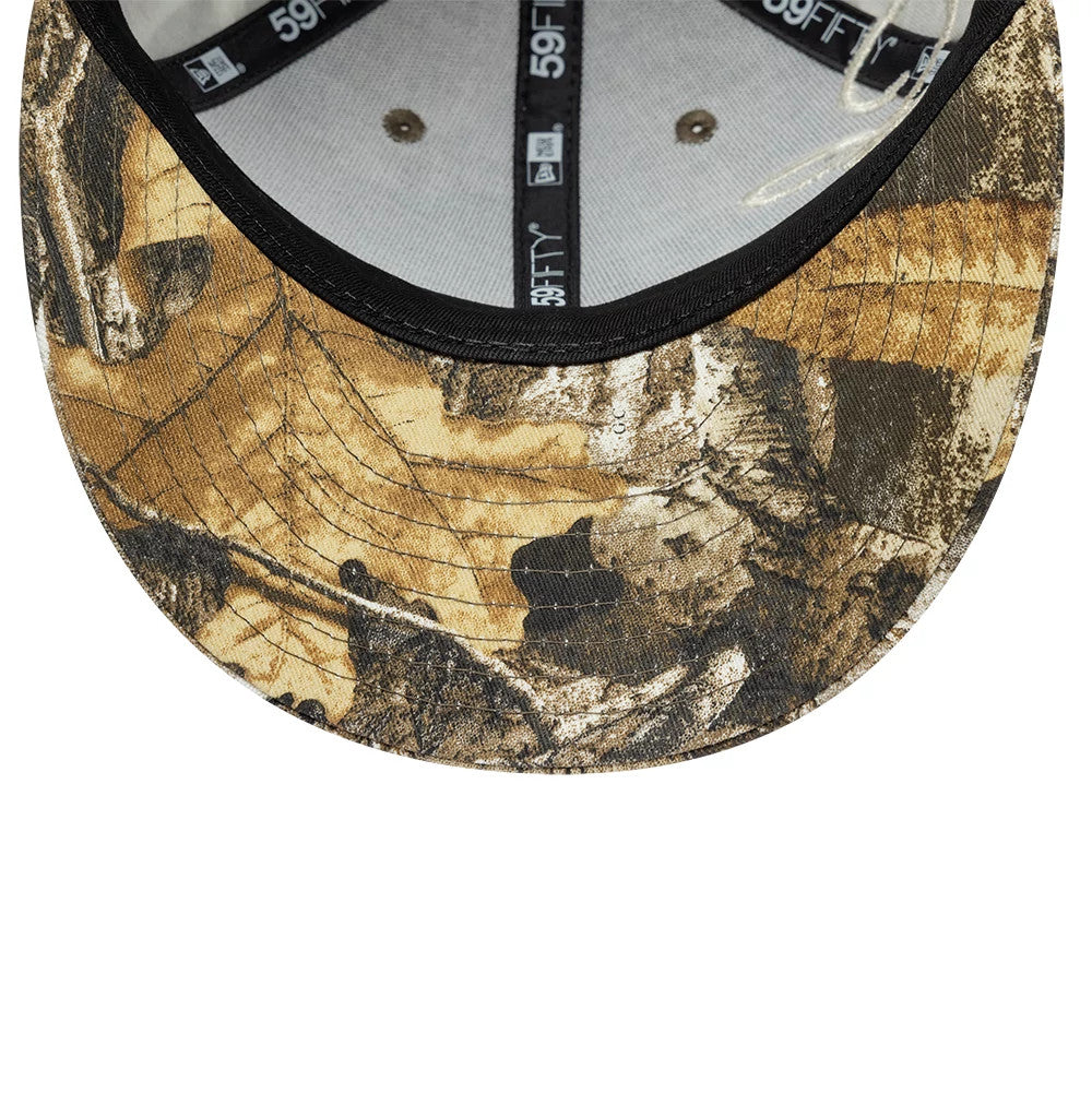 New Era Side Script Realtree Camo Low Profile 59FIFTY Fitted Cap, inside view showing black taping with repeated 59FIFTY branding, a camo undervisor pattern with stitching detail, and a white sweatband.