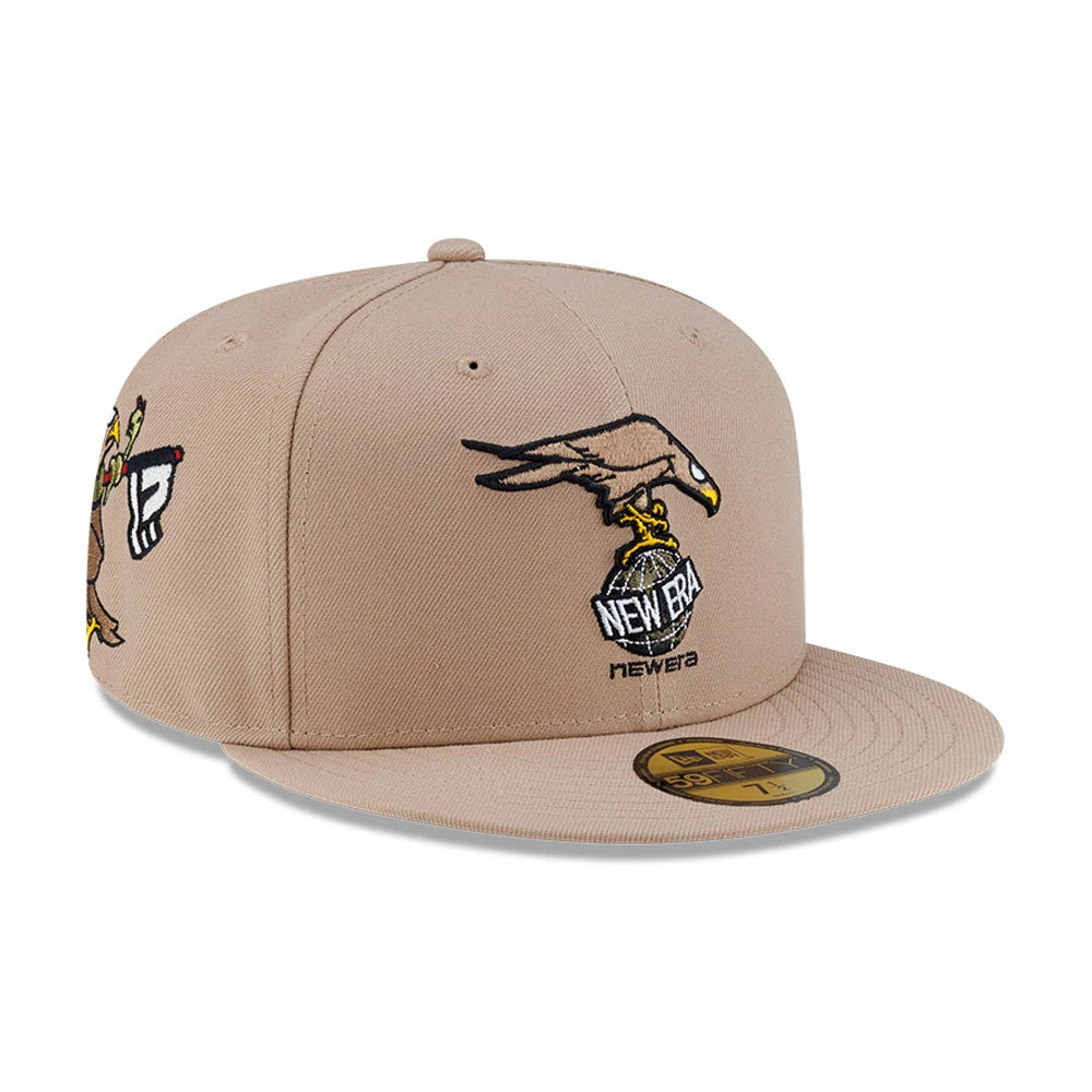Roji Soccer Beige New Era 59FIFTY Fitted Cap, three-quarter view showing the detailed embroidery of an eagle clutching a New Era logo on the front panel, with additional side embroidery and a beige flat visor featuring a gold 59FIFTY size sticker.