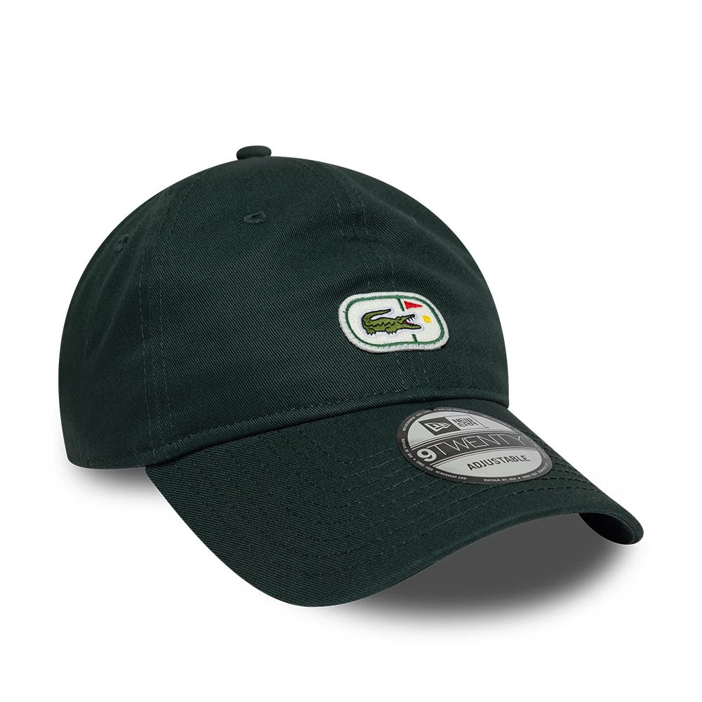 Lacoste X New Era Dark Green 9TWENTY Adjustable Cap, three-quarter view showing the embroidered Lacoste crocodile logo on the front panel, a dark green unstructured crown with eyelets, and the 9TWENTY size sticker on the curved visor.