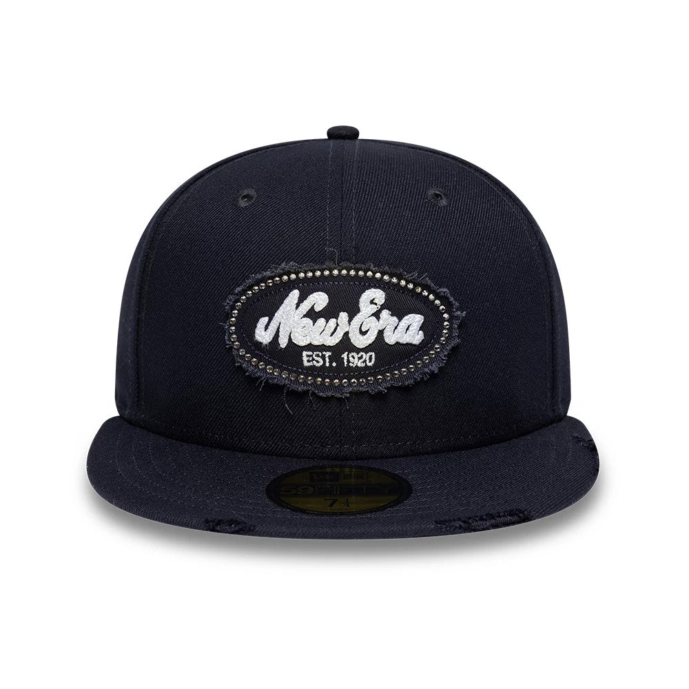 New Era Gem Patch Distress Navy 59FIFTY Fitted Cap, front view showing the intricately embroidered oval New Era patch on the structured navy blue front panels, with distressed details on the visor and a gold 59FIFTY size sticker.