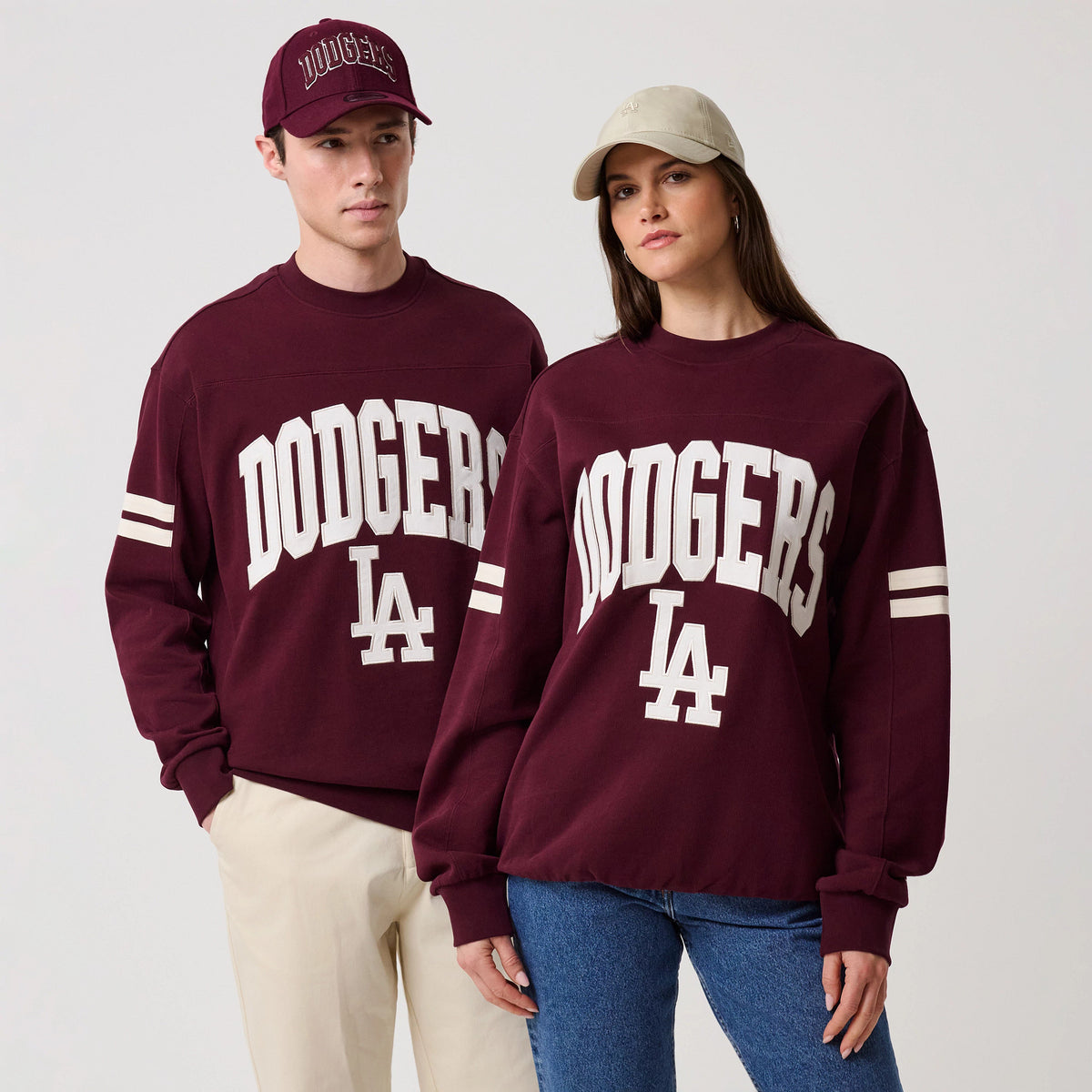 New Era LA Dodgers MLB Arch Graphic Dark Purple Crew Neck Sweater, front view on models wearing matching sweaters with large white embroidered Dodgers lettering across the chest, contrasting white LA logo beneath.