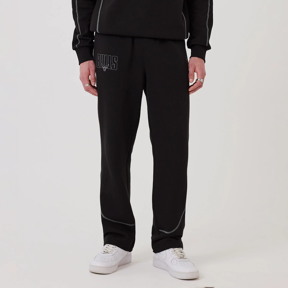 New Era Chicago Bulls NBA Graphic Black Straight Leg Joggers, front view on a model wearing white trainers, featuring the Bulls logo embroidered on the upper left leg and seam towards the ankles.