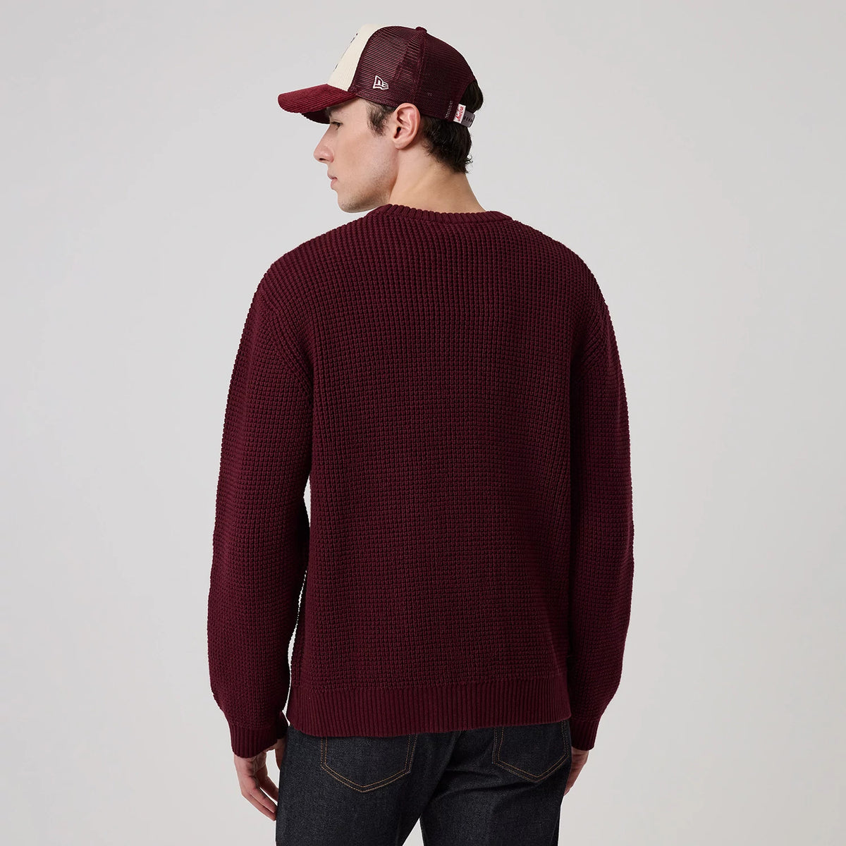 New Era New York Yankees MLB Waffle Knit Dark Purple Crew Neck Sweater, back view on a model wearing a matching cap, showing the textured waffle knit pattern and ribbed cuffs and hem, highlighting the deep dark purple colour against dark denim jeans.