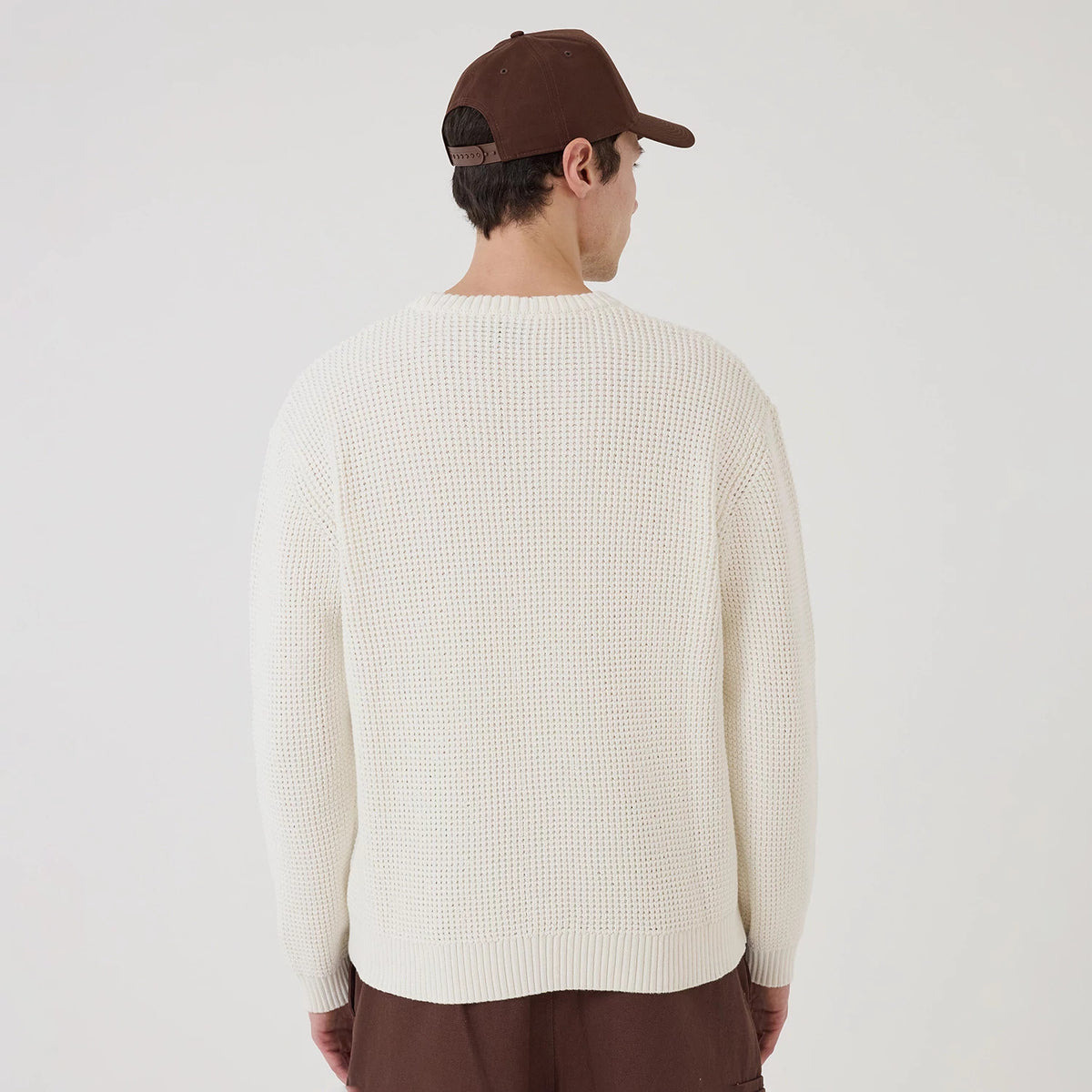 New Era LA Dodgers MLB Waffle Knit Open White Crew Neck Sweater, back view on a model wearing a brown cap, featuring a textured waffle knit pattern, a ribbed hem and cuffs, and a relaxed white fit covering the shoulders and upper back.
