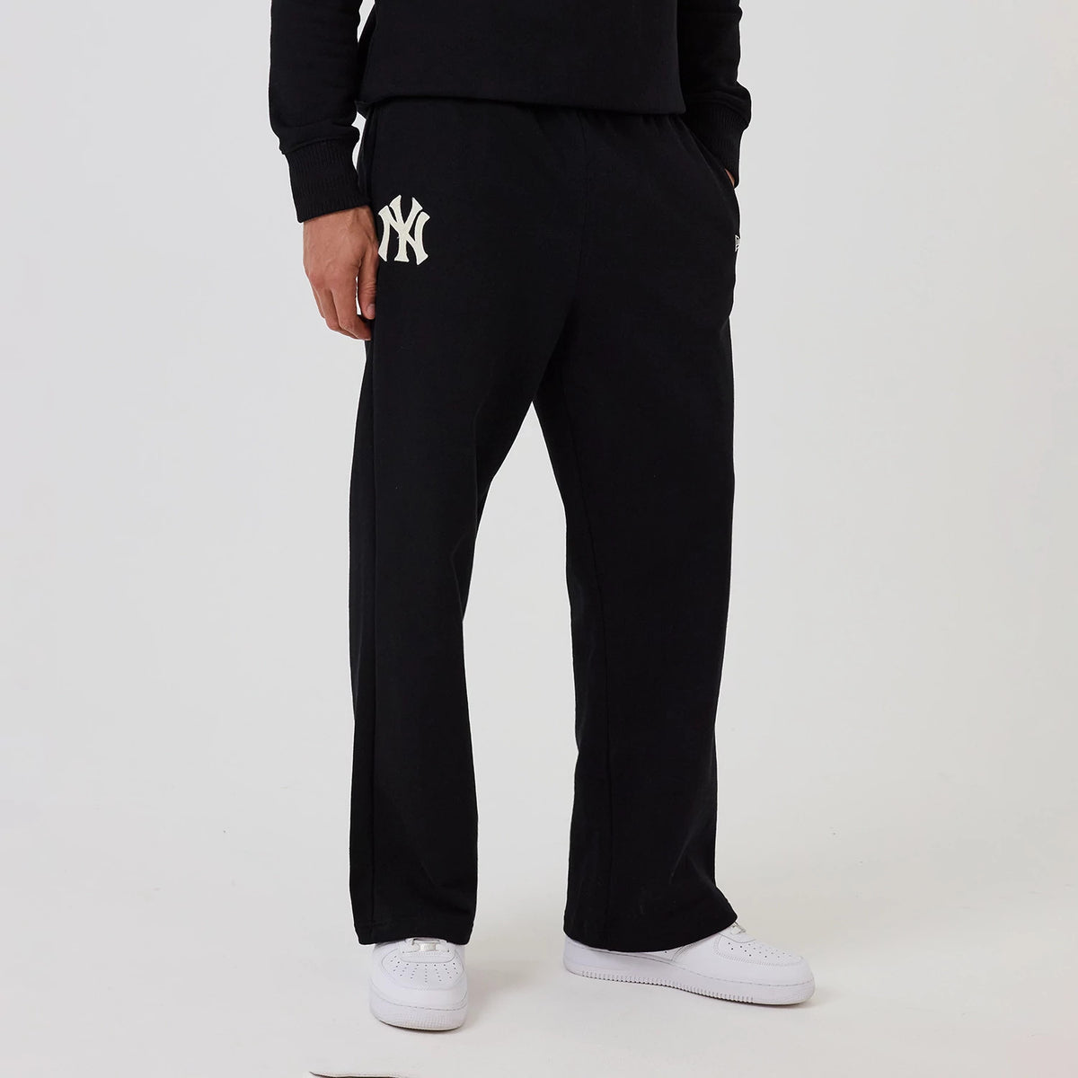 New Era New York Yankees MLB Black Wide Leg Joggers, front view on a model featuring the white Yankees logo on the upper left thigh, loose fit through the leg, and paired with white trainers for a casual look.