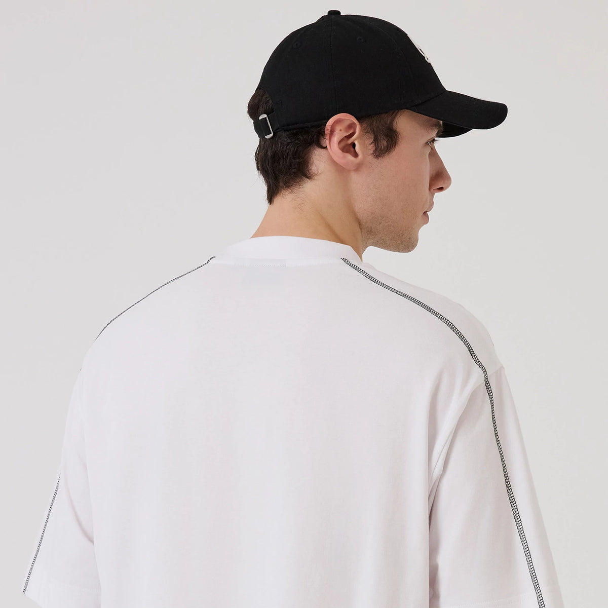 New Era Chicago Bulls NBA Graphic White Boxy T-Shirt, back view on a model wearing a black cap, featuring stitching along the seams, a relaxed fit and a clean white surface with no graphics or logos.
