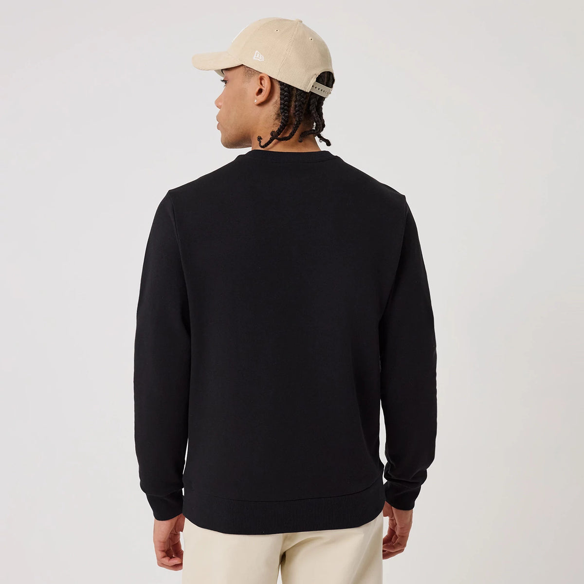 New Era New York Yankees MLB Linear Black Crew Neck Sweater, back view on a model wearing a cream New Era cap, showcasing a clean and simple black design with long sleeves and ribbed cuffs and hem.
